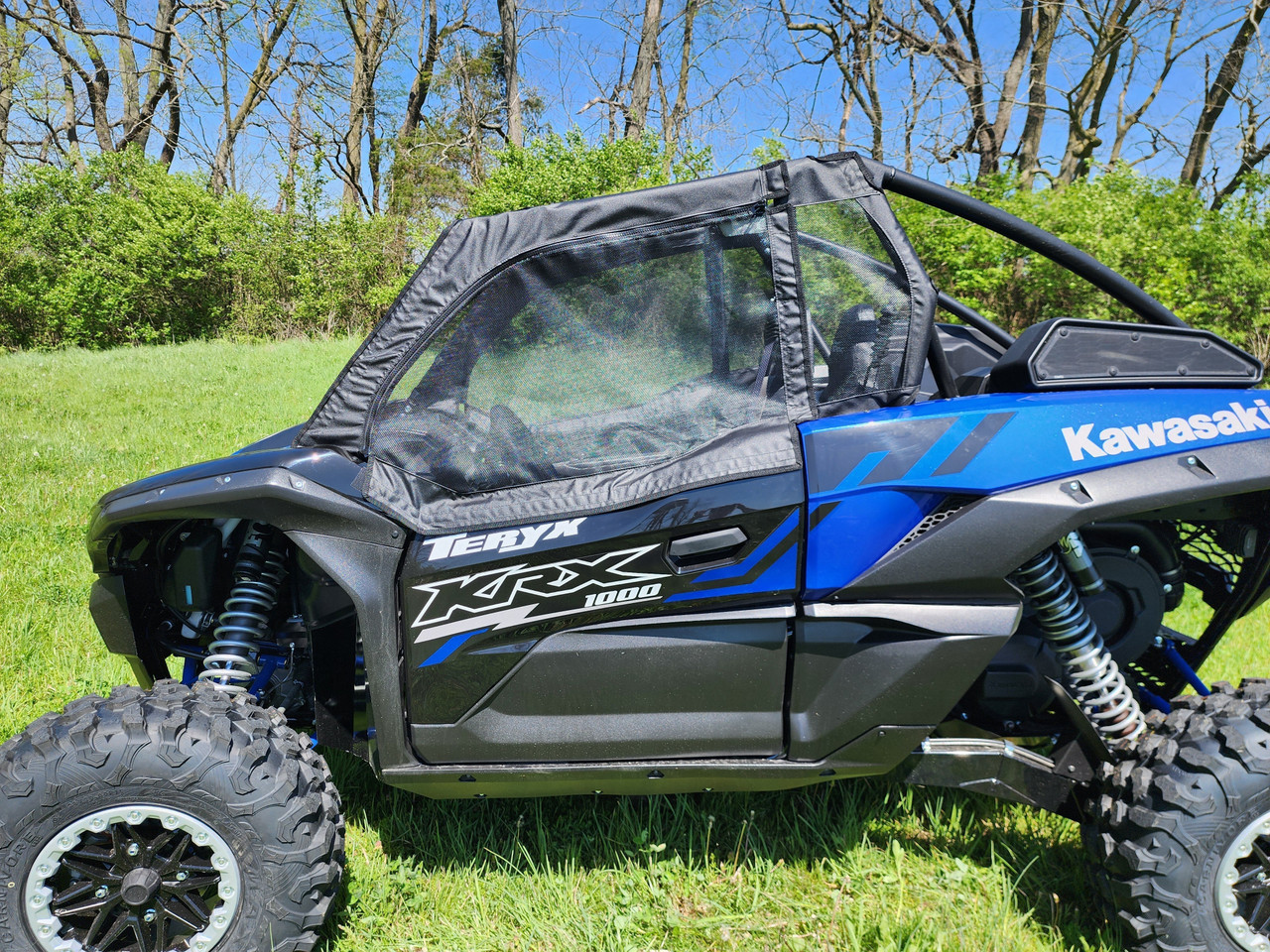3 Star upper doors with mesh windows on a blue Kawasaki Teryx KRX, driver side close-up in a field