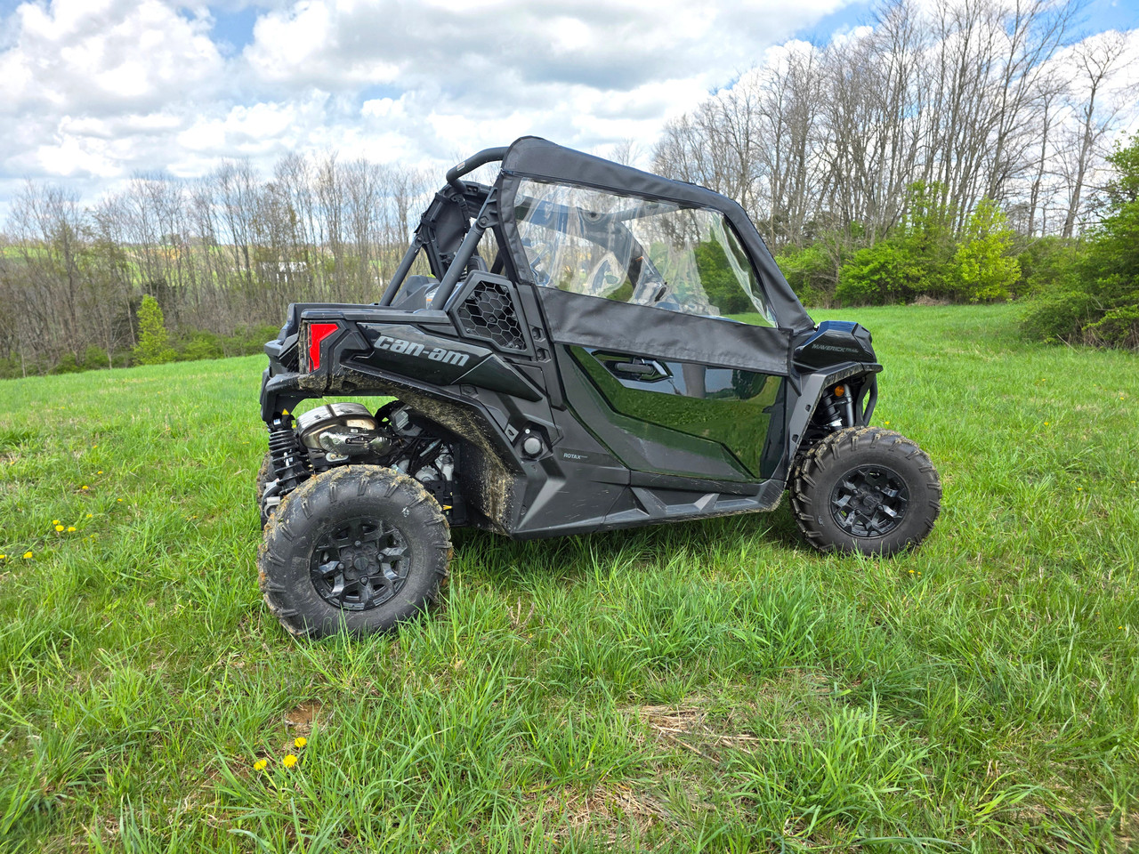 3 Star upper doors on a black Can-Am Maverick Trail with clear windows, driver side profile in a green field