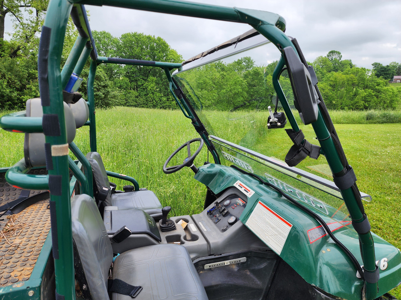 Driver side view of the 3 Star two-piece windshield clamped to the green cage of an older Polaris Ranger