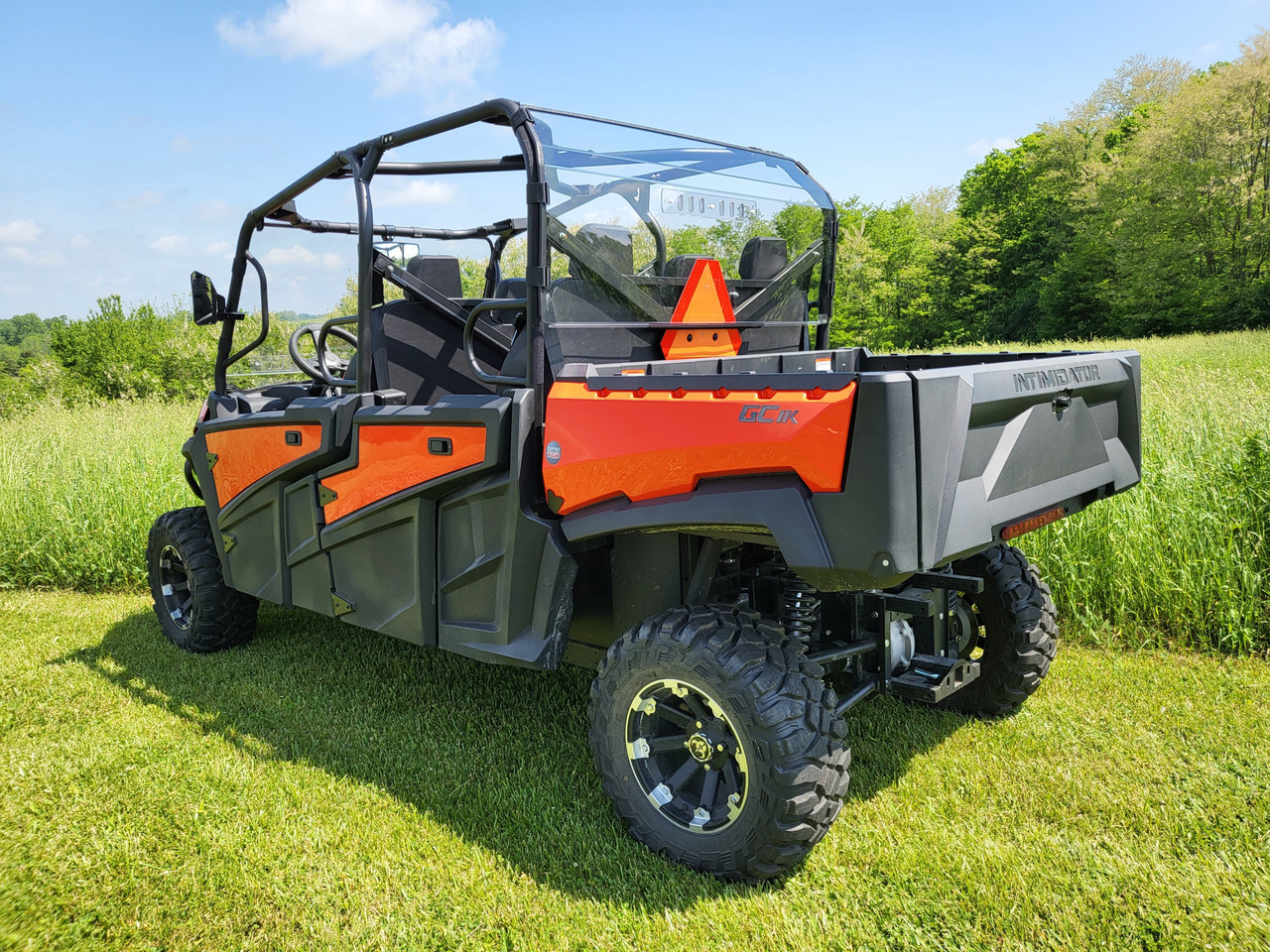 3 Star polycarbonate rear windshield installed on an orange six-seat side-by-side, rear three-quarter view in a field