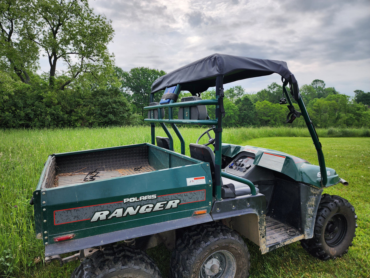Rear three-quarter view of a green 1999 Polaris Ranger with the 3 Star canvas top over the cab and dump bed