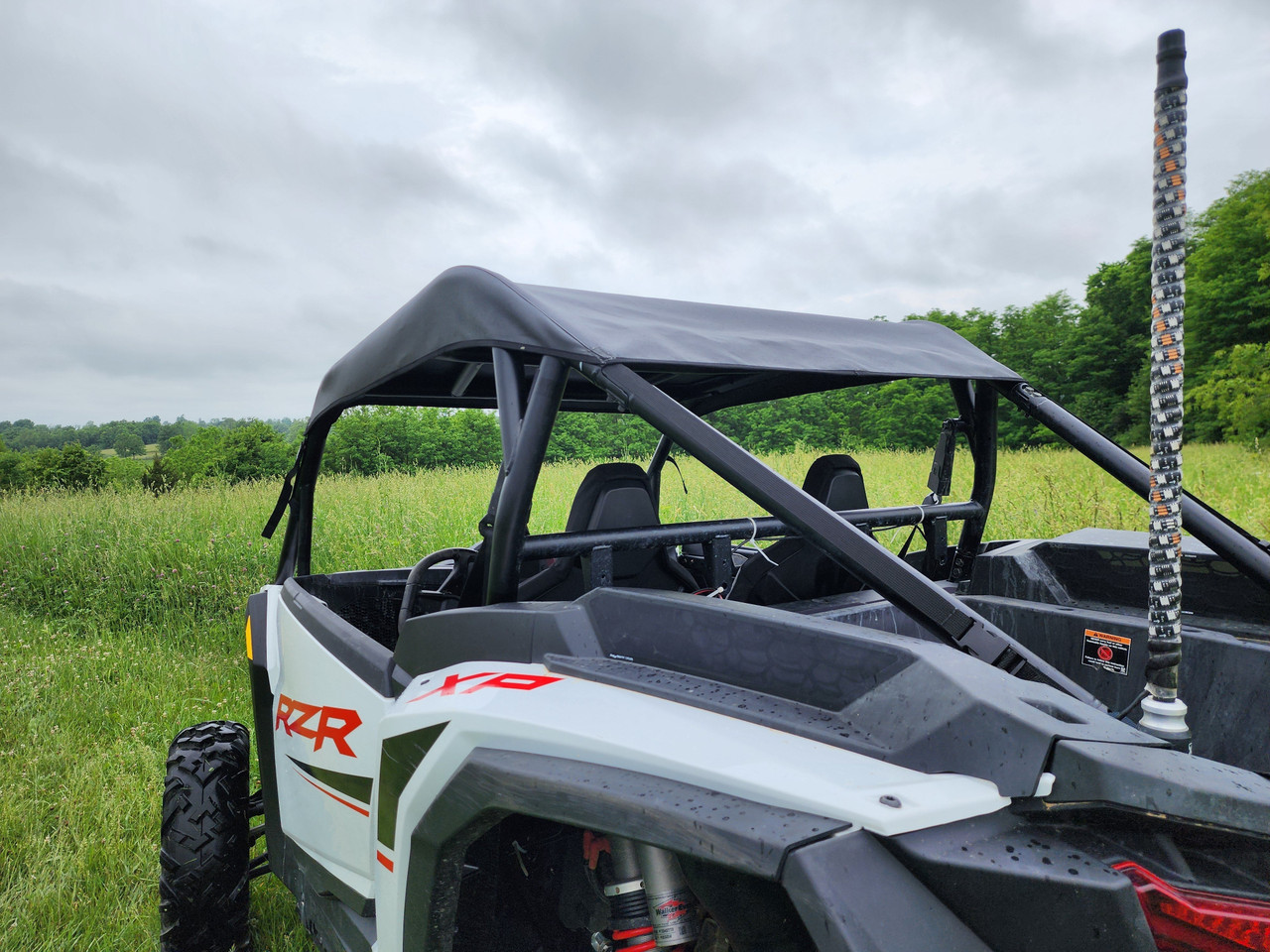 Rear corner view of the 3 Star canvas top on the white 2024-2025 Polaris RZR XP 1000 cage in a field
