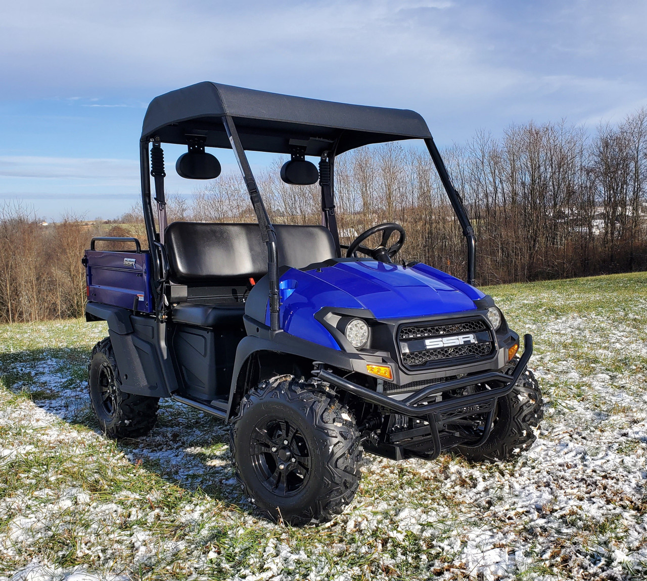 3 Star black soft top on a blue Bison utility side-by-side, front three-quarter view in a snowy field