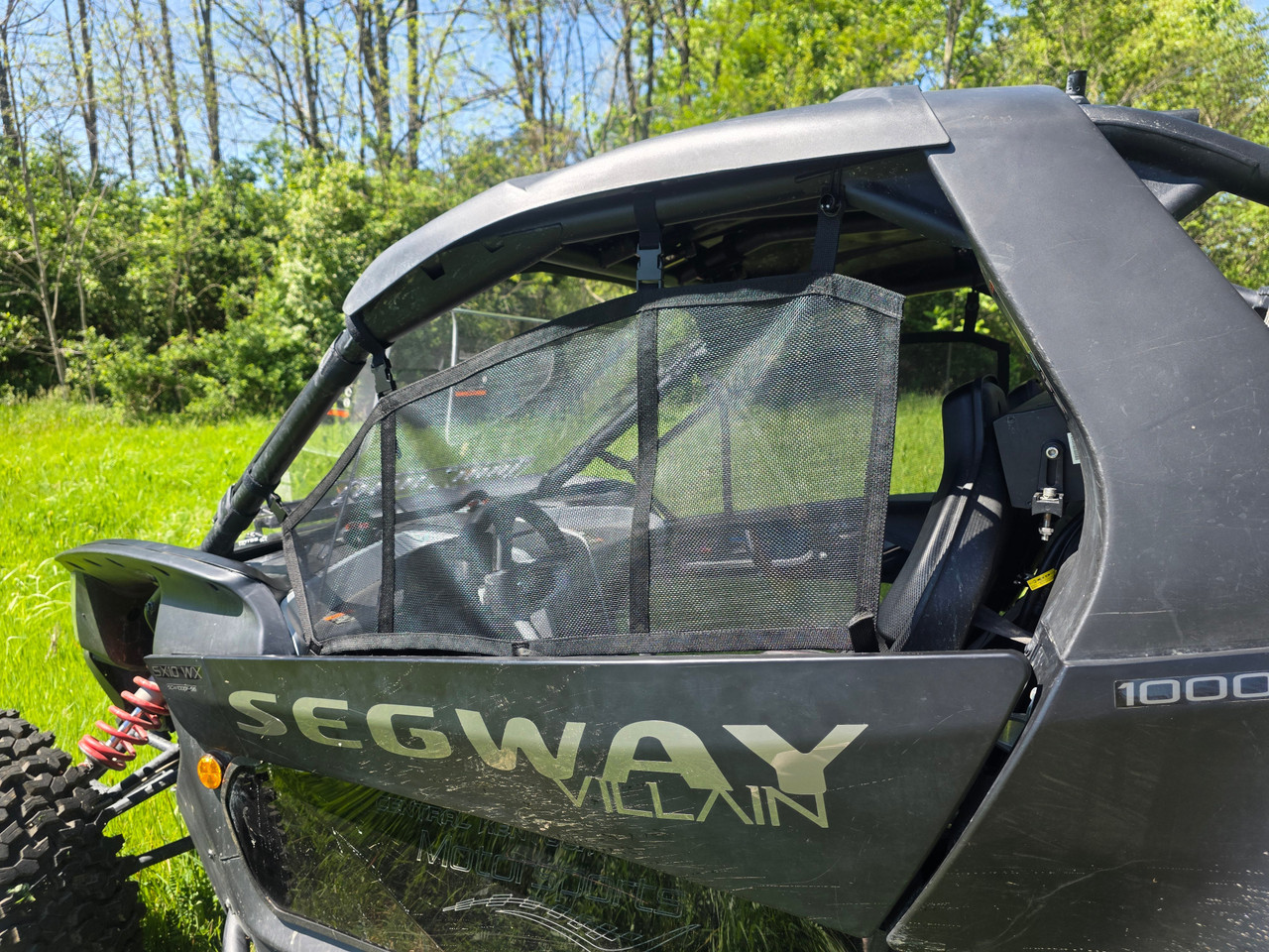 Passenger side view of the 3 Star safety net stretched across the door opening of a Segway Villain in a field