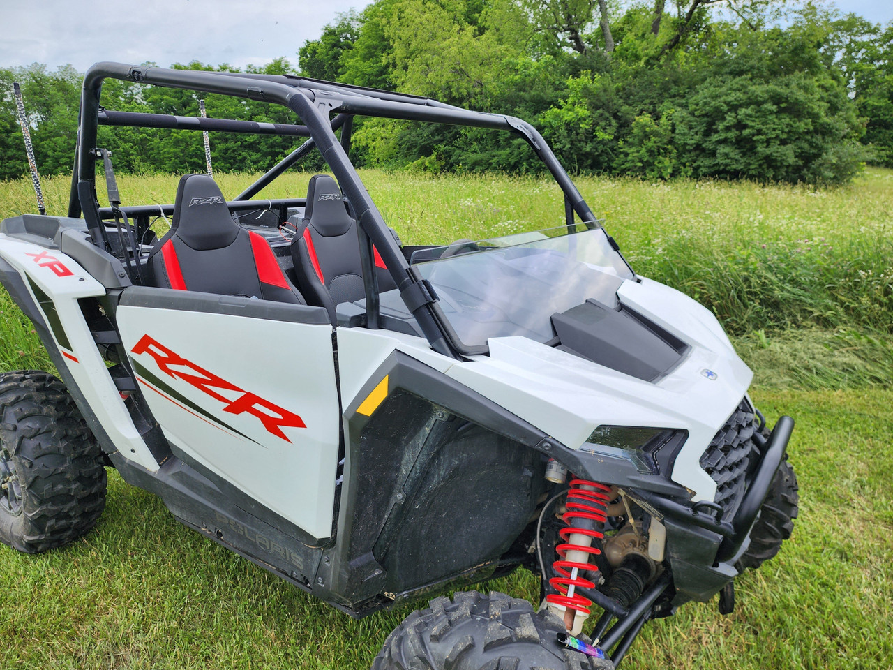 Front three-quarter view of a white Polaris RZR XP 1000 with red seats wearing the 3 Star half windshield