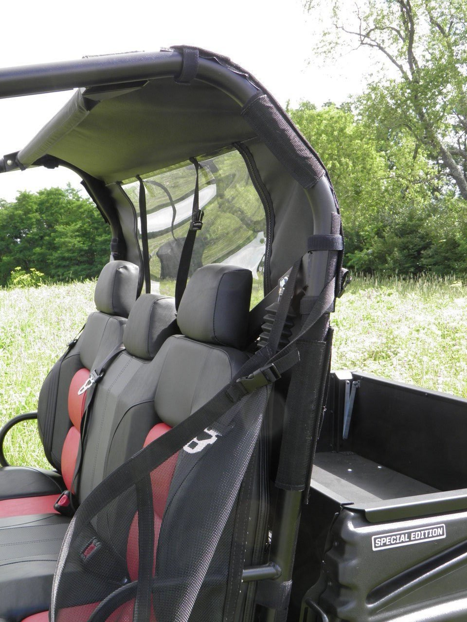 3 Star soft back panel with clear window behind the red and black seats of a side-by-side, viewed from the side