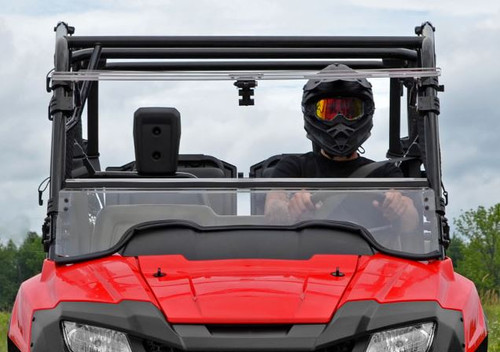 Straight-on front view of the red Honda Pioneer 700 with the SuperATV windshield fully closed and a helmeted rider