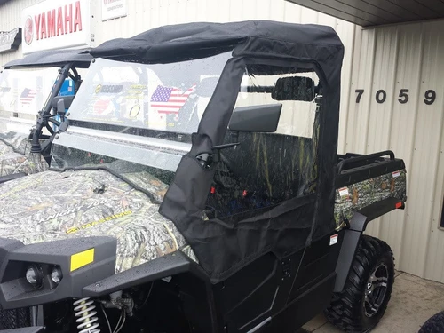 Side X Side cab enclosure for Bennche Cowboy 500/700 on a camo side-by-side, driver side view by a shop