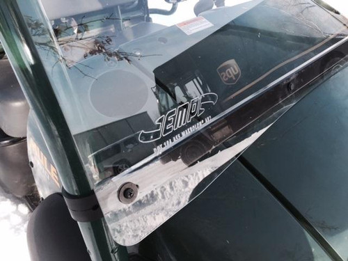 Close-up of the Extreme Metal Products windshield lower edge, clamp and EMP decal on the green Kawasaki Mule 600/610 hood