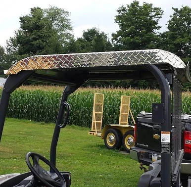 Close-up of the Wiedmann Bros diamond plate aluminum roof on a Kubota RTV, showing the tread texture and edge