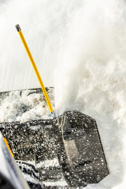 Kolpin snow plow blade wing on a black plow pushing snow, close-up with yellow marker pole