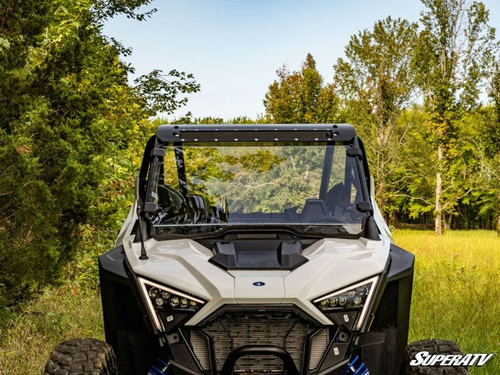 Front view of a white Polaris RZR Pro XP with the SuperATV full windshield installed in a wooded clearing