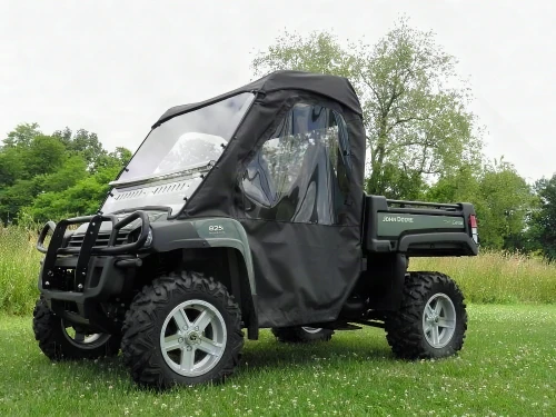 3 Star full cab enclosure installed on a green John Deere Gator XUV with brush guard, front three-quarter view