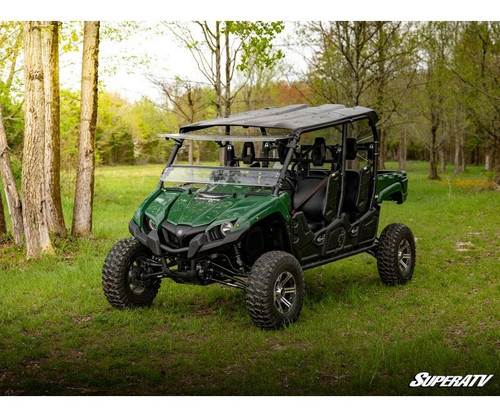 SuperATV 4-inch lift kit installed on a green six-seat Yamaha Viking in the woods, front three-quarter view