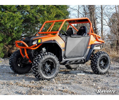 Front three-quarter view of an orange Polaris RZR with SuperATV aluminum doors closed, parked on gravel