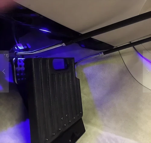 Sure Grip gas and brake guard installed in a vehicle footwell under blue interior lighting, angled view