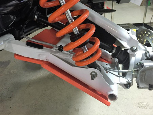 Trail Armor orange A-arm guard installed on a front lower A-arm of a Polaris General 1000, close-up