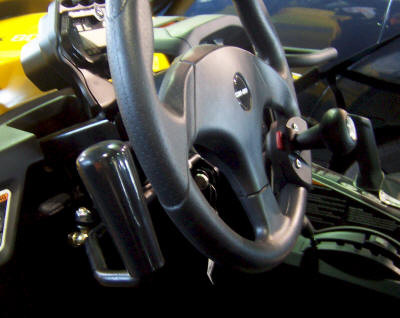 Sure Grip hand control lever mounted left of the steering wheel in a yellow Can-Am side-by-side cab, close-up