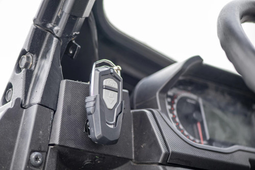 Kolpin wireless winch remote fob mounted on the dash of a side-by-side next to the gauge cluster