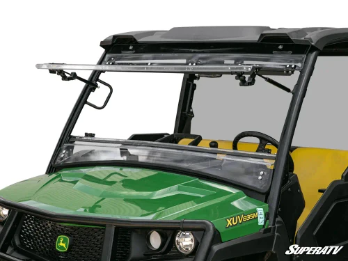 SuperATV scratch-resistant flip windshield installed on a green John Deere Gator XUV835, front close-up