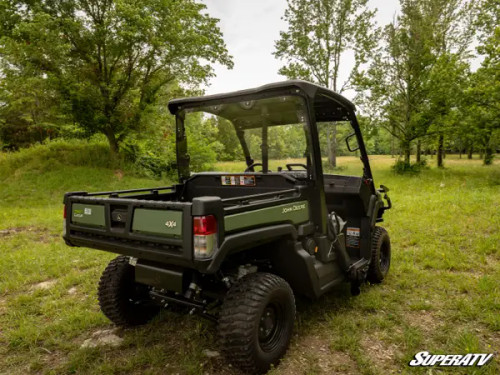 Rear three-quarter view of a green John Deere XUV865 with the SuperATV rear windshield installed in a field