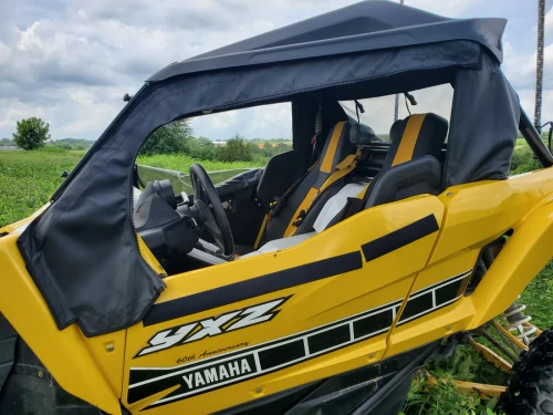 3 Star black soft doors with clear windows installed on a yellow Yamaha YXZ 1000R, driver side view in a field