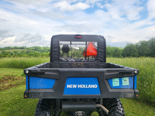 3 Star soft back panel on a blue New Holland 850 Crew, straight rear view over the cargo bed with the clear window above
