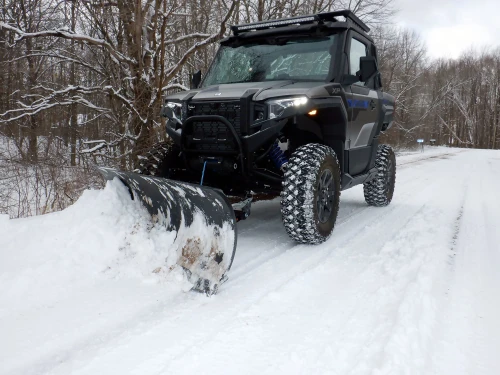 Kolpin Front-Connect plow mount on a Polaris Xpedition with the plow blade pushing snow on a road