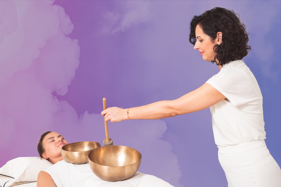 Practitioner playing singing bowls over a client during hands-on VST Hybrid training