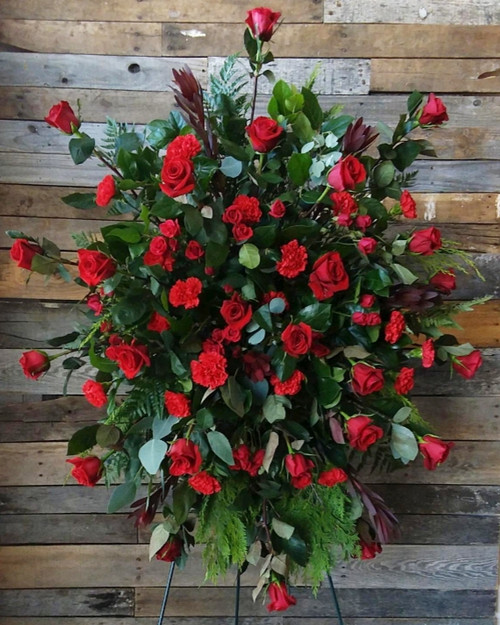 An all red standing spray filled with gorgeous red roses and lush greenery.