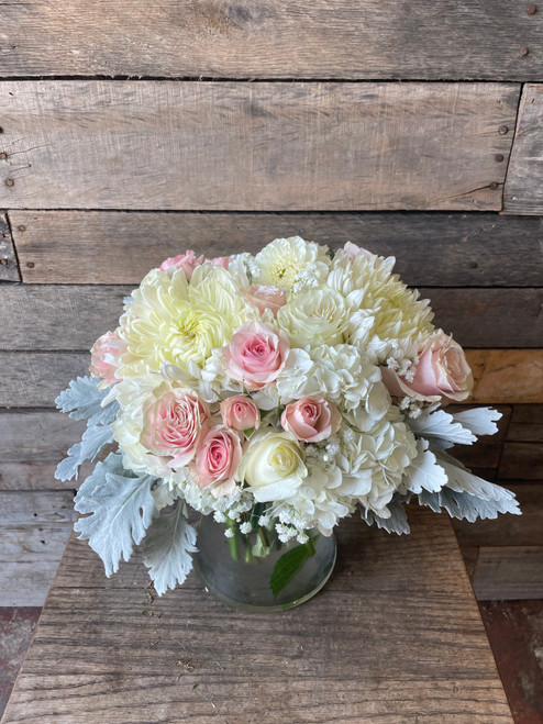 Blush pink and creamy white roses nestled among white hydrangea and large ivory chrysanthemums.