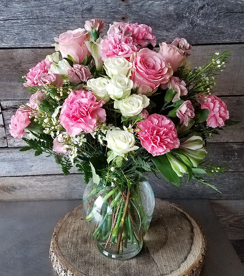 a mix of pinks and whites with pink roses, carnations, and white and pink filler all in a clear glass vase