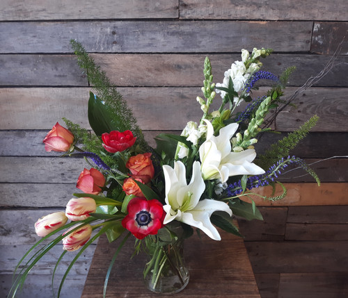 A mix of white lilies and and snapdragons with orange roses and seasonal accent flowers