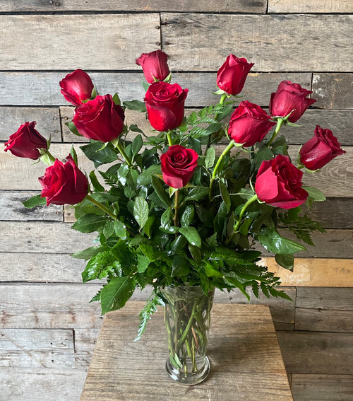 A dozen long stemmed red roses in a vase for Valentine's Day.