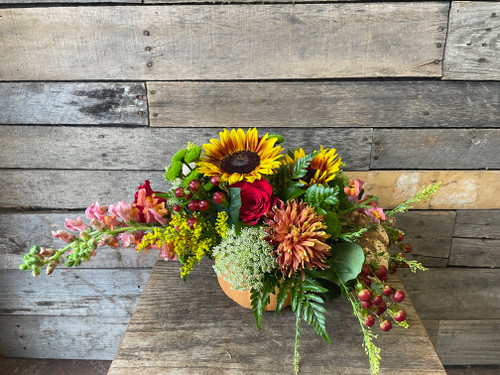 Sunflowers, chrysanthemums, hypericum berries, solidago, snapdragons, with fresh seasonal greenery in a pumpkin shaped vase.