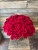 One hundred velvety long stemmed red roses arranged snugly in a large vase.