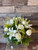 White roses, lilies surrounded by snapdragons, delicate veronica, baby’s breath, golden solidago, eucalyptus, and lush fresh greenery