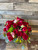 twenty-four red roses with hypericum berries, eucalyptus, and complimenting filler flowers for a textured look in a large, clear glass vase