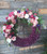 This unique and feminine fresh floral wreath has a pleasing shape, with the upper curve wild with soft pinks and purple roses, daisies, and greenery, with the lower curve consisting of a very uniform blanket of purple mums. Definitely one of a kind!