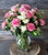 a mix of pinks and whites with pink roses, carnations, and white and pink filler all in a clear glass vase