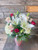 Pink and red roses, hydrangea, daises, and lillies in a rosy pink vase with fresh green foliage.  