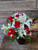 Red roses, white daisies, white lilies, red spray roses with greenery and filler in a ruby red vase.
