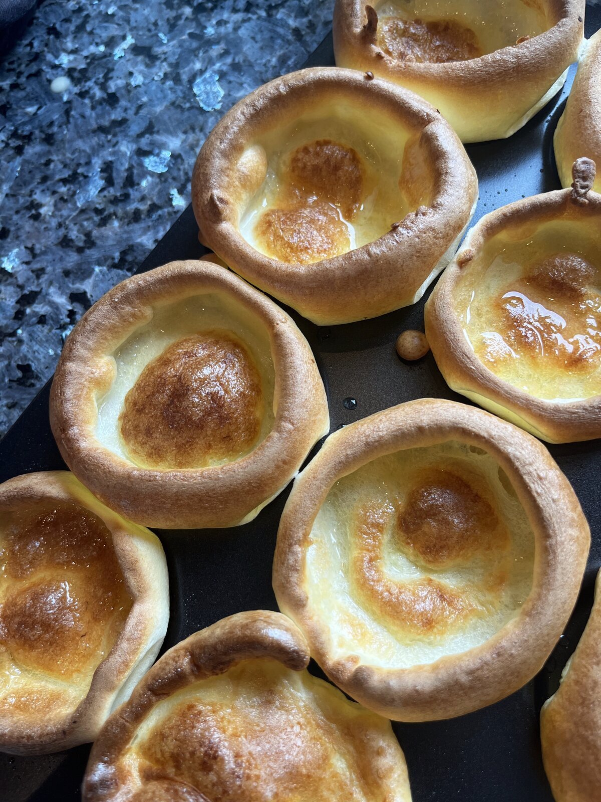 Top-down view of a risen Yorkshire pudding in a Wrenbury tin showing the open crisp shell and gravy well