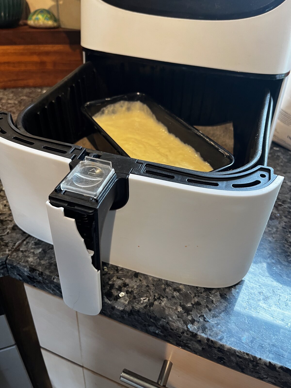 1lb loaf tin lowered into an air fryer basket with space around it