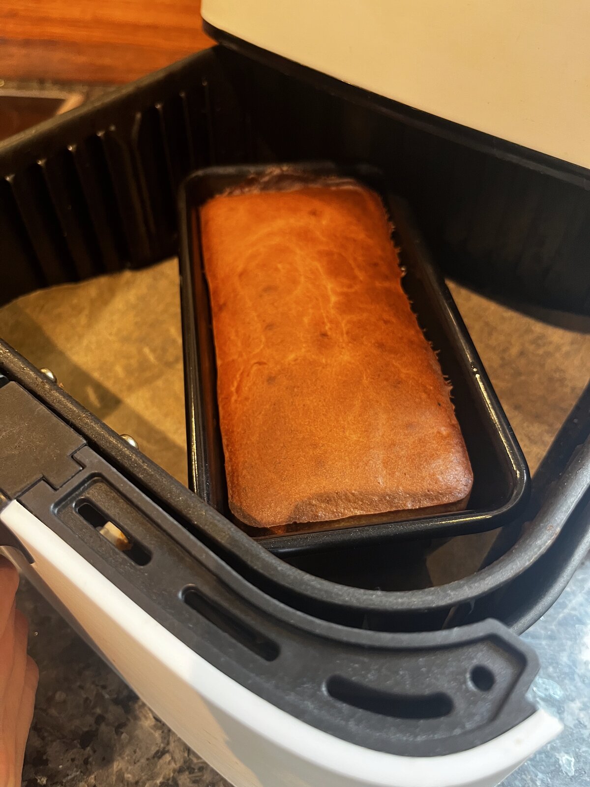 Golden banana bread in a 1lb loaf tin sitting inside an air fryer basket