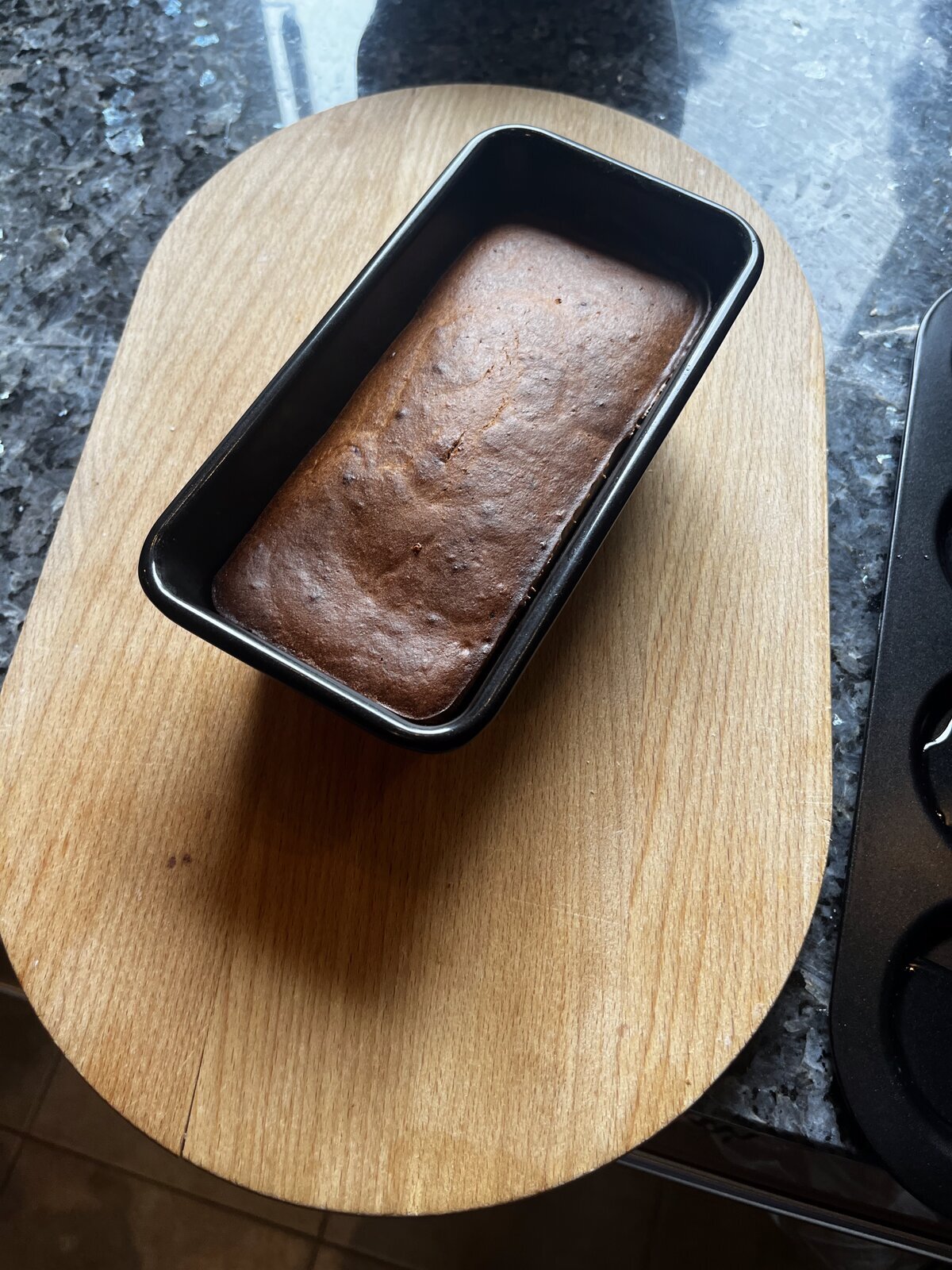 Finished banana bread loaf turned out of the tin onto a wooden board