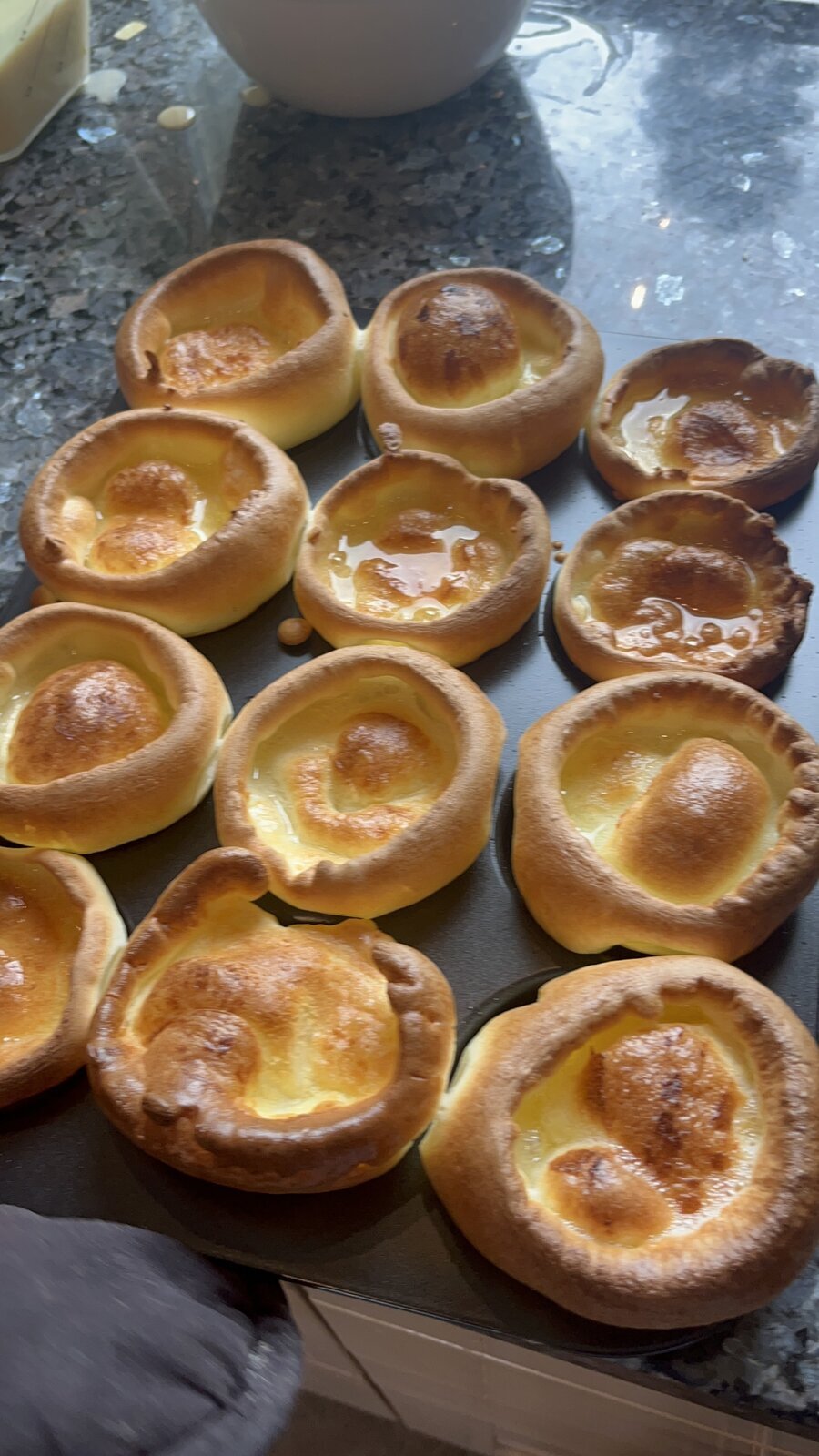 A dozen golden, risen Yorkshire puddings fresh from the oven, glossy with hot fat in each well