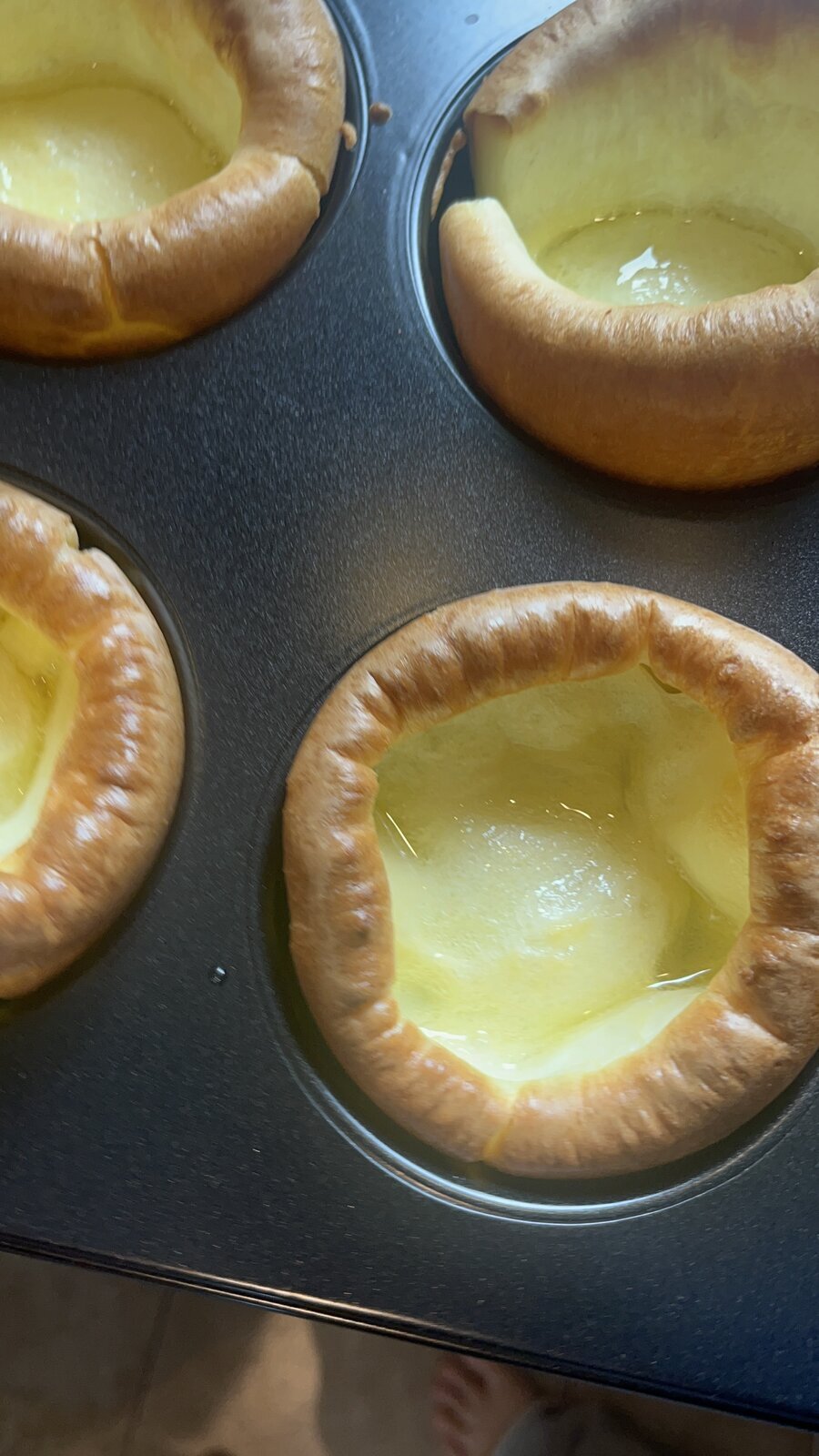 Close-up of deep jumbo Yorkshire puddings in the tray, golden with hot fat pooled in the wells