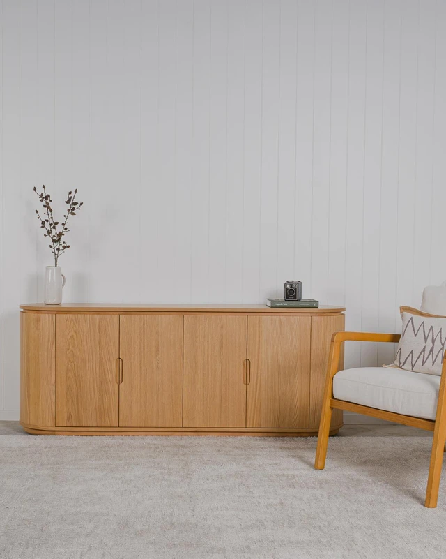 natural oak sidebaord with curved ends against a white panelled wall