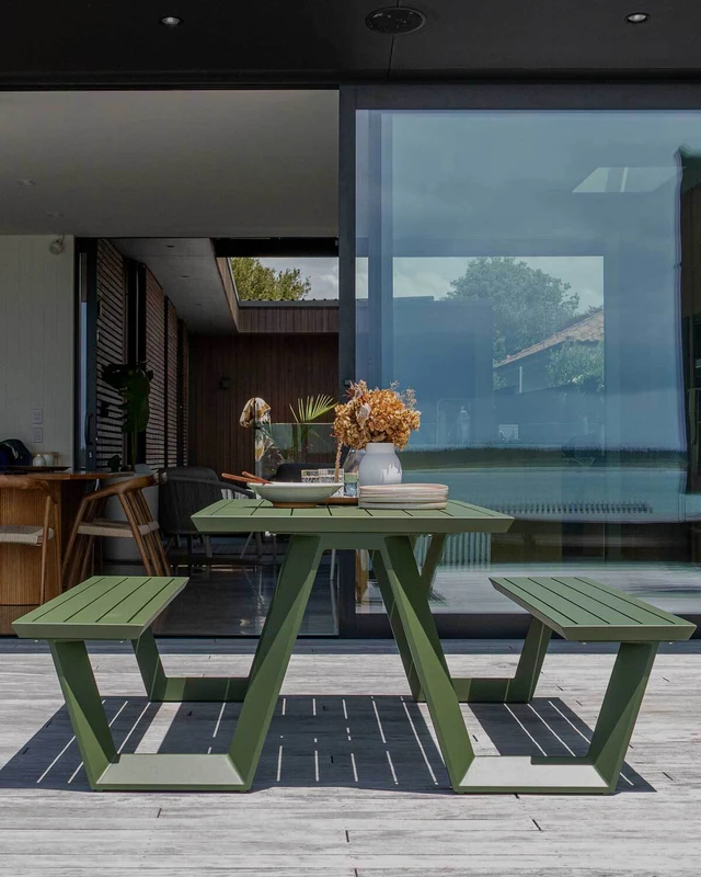 Tahoe outdoor picnic table in forest green with slatted table top and bench seats, styled on a timber deck overlooking the water.